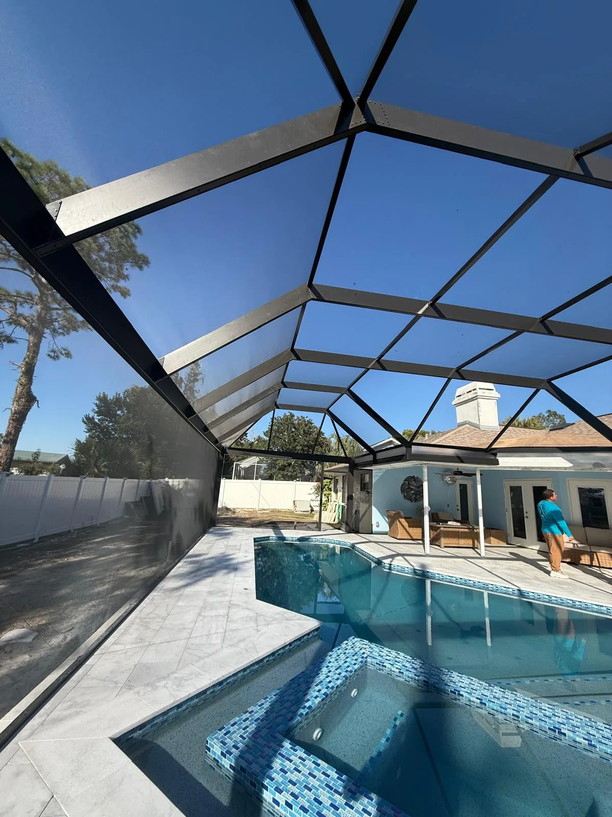 Custom pool cage enclosing pool and spa under blue Florida sky