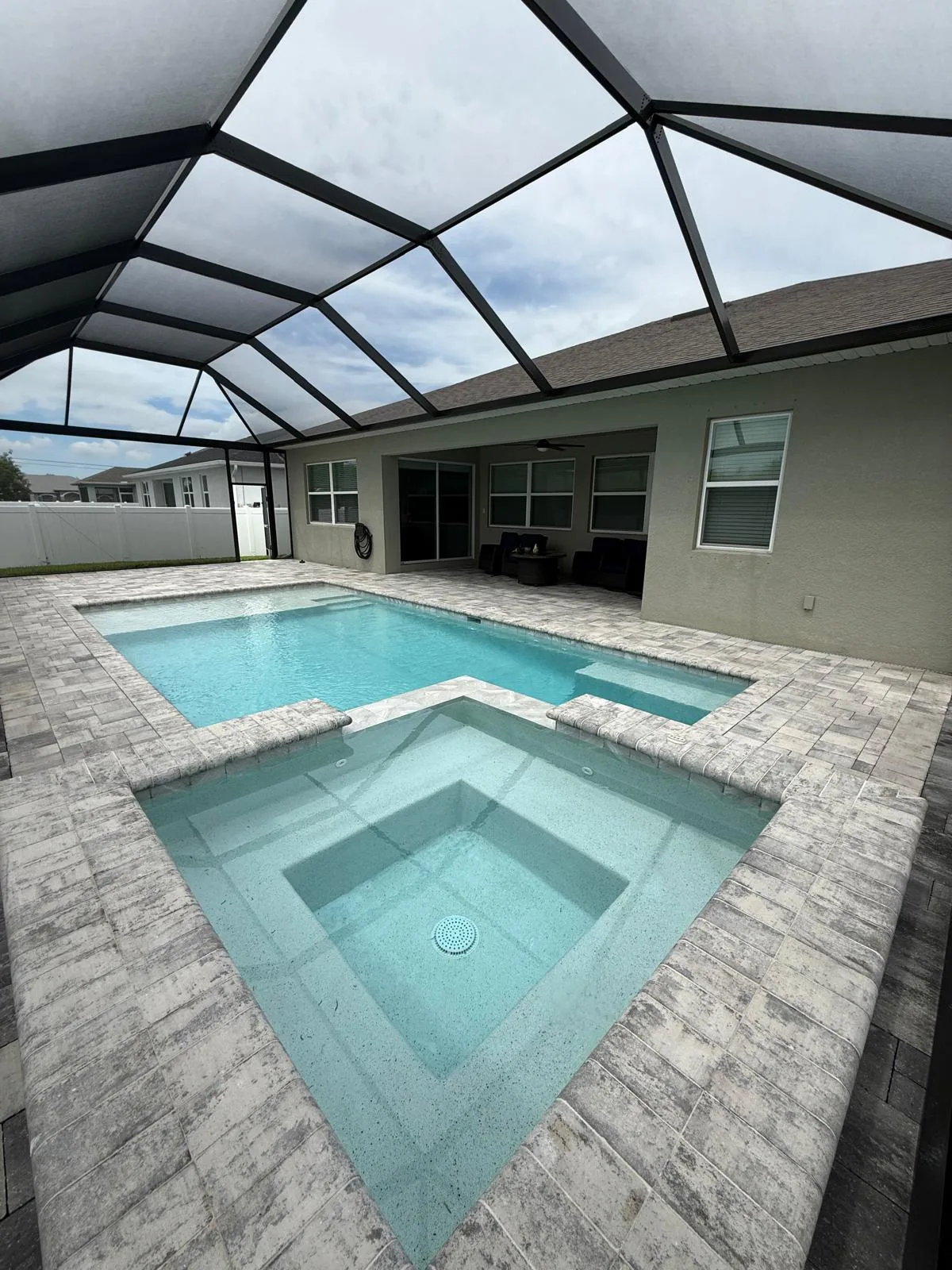 New aluminum pool cage with travertine paver deck enclosing pool and spa in Southwest Florida