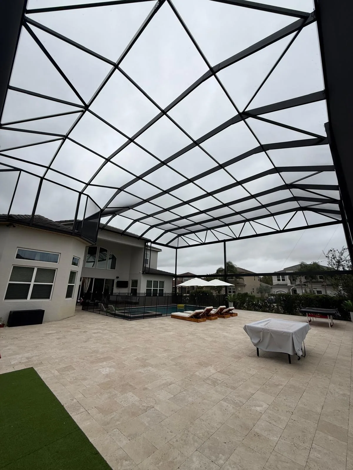 After — completed large custom pool cage interior with patio furniture and umbrellas, Florida