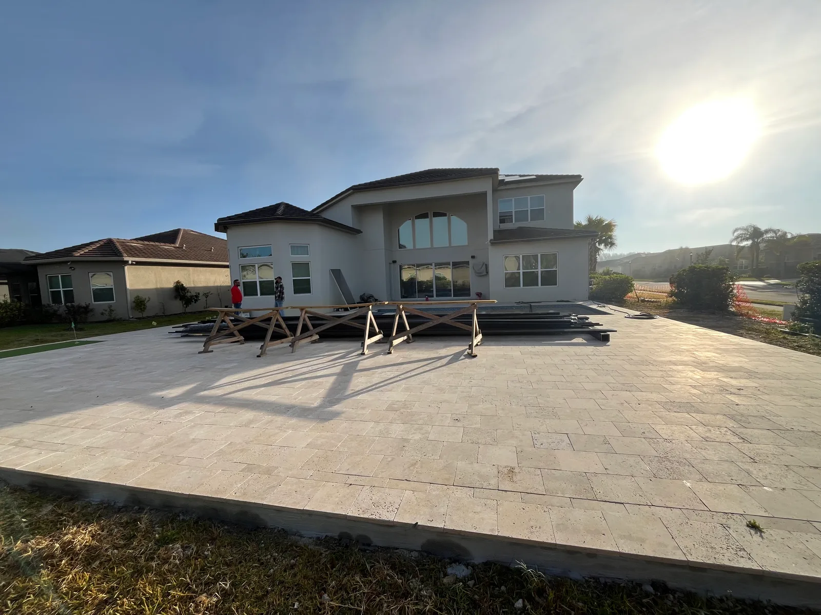 Before — freshly laid paver deck with pool cage aluminum materials staged for installation, Florida