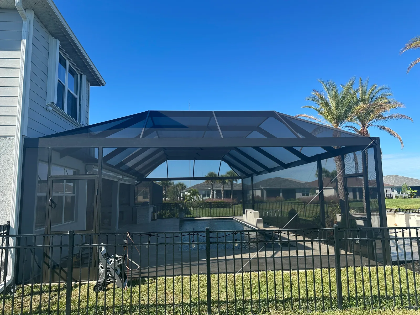 Exterior of screened pool cage enclosure on Florida home with palm tree, Cape Coral