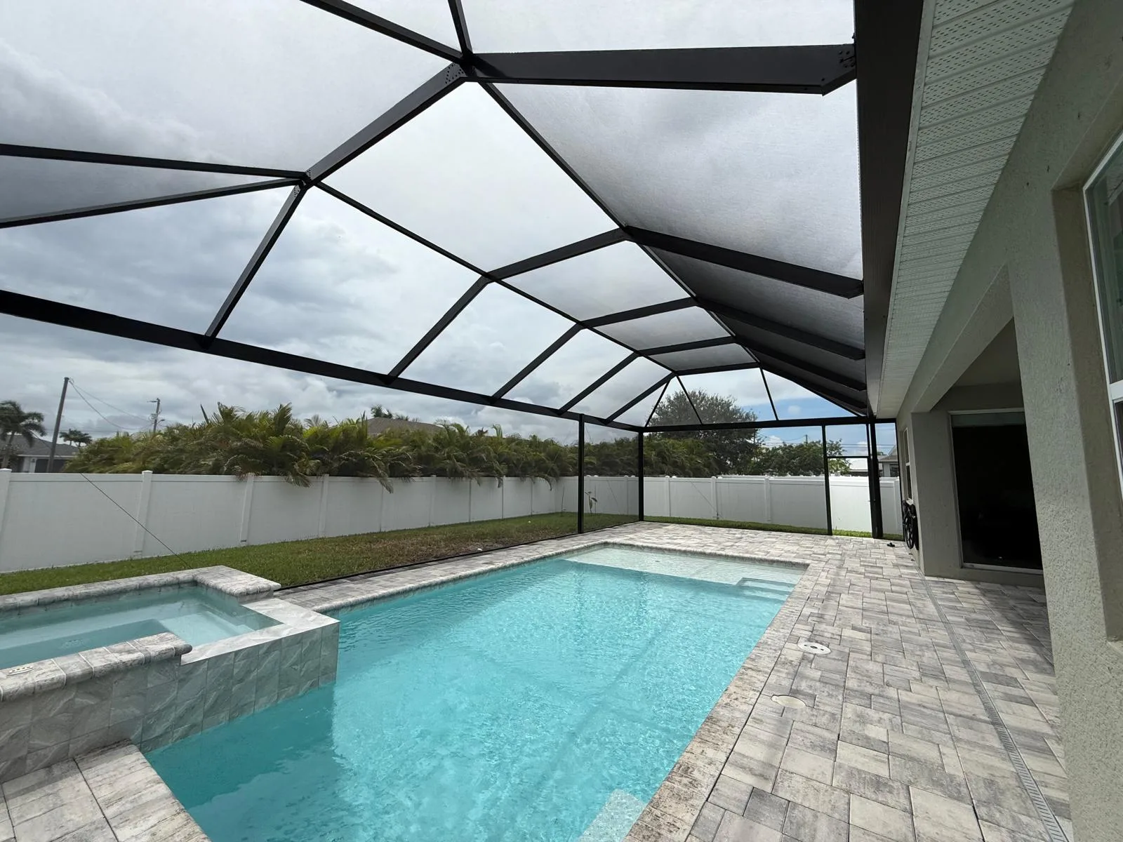 Wide aluminum pool cage enclosing pool and spa with paver surround in Southwest Florida