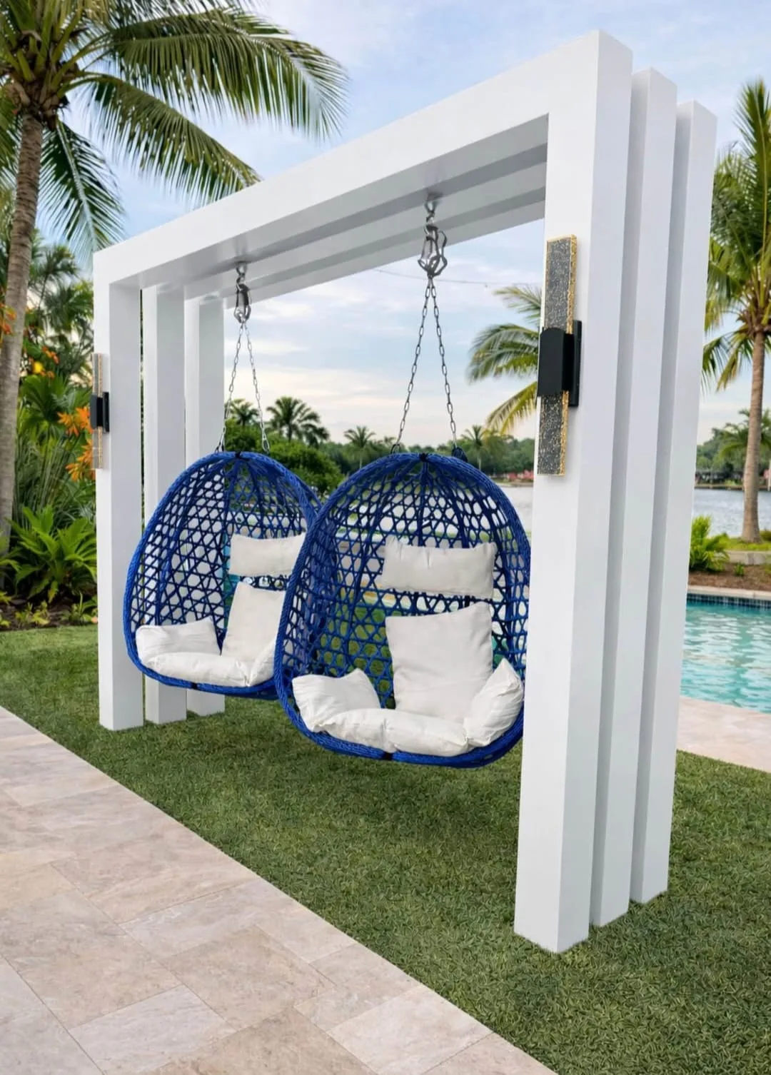 Custom white aluminum pergola with two hanging egg chairs, palm trees and waterfront view in Southwest Florida