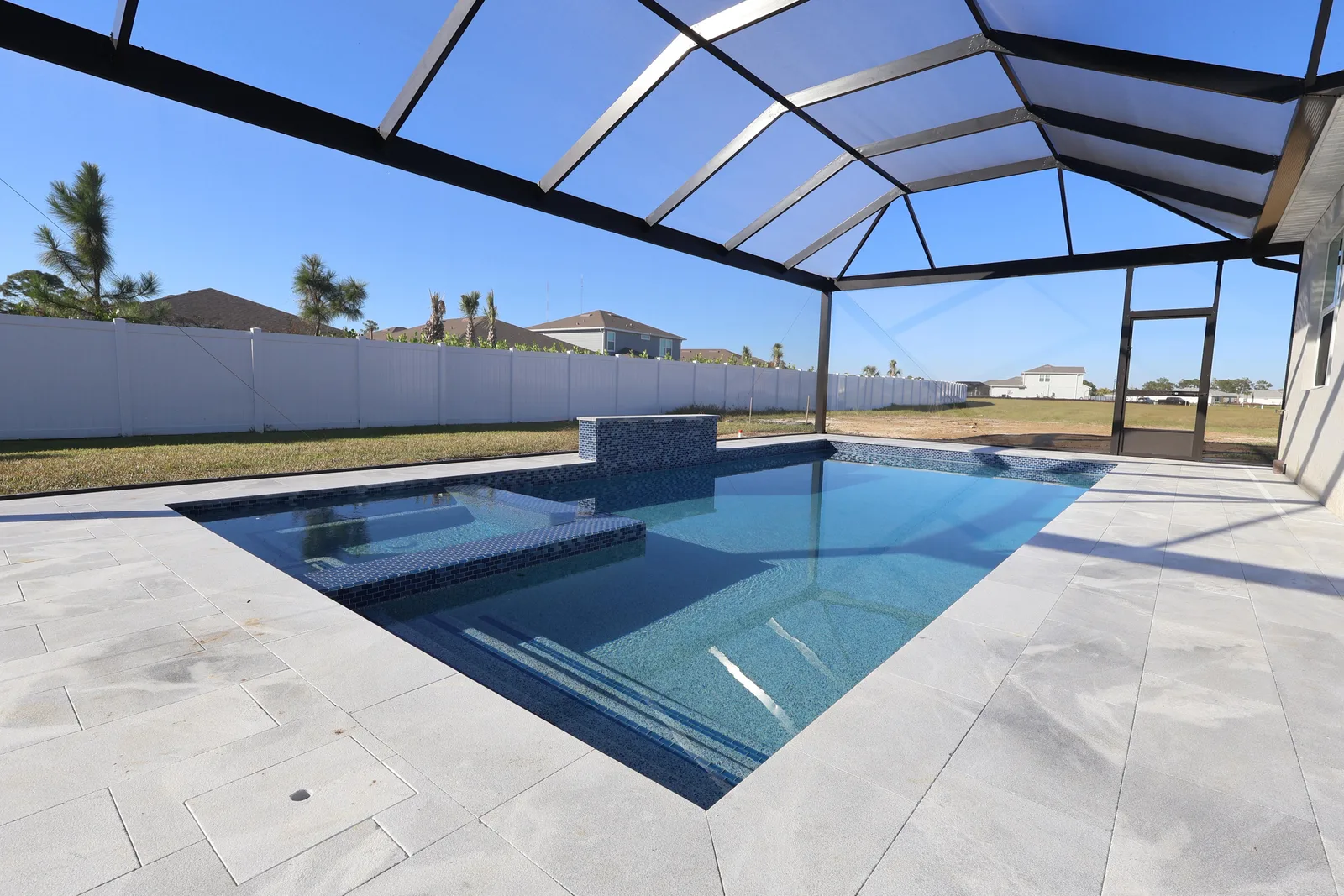 Brand new aluminum pool cage enclosing rectangular pool and spa with travertine paver deck in Florida